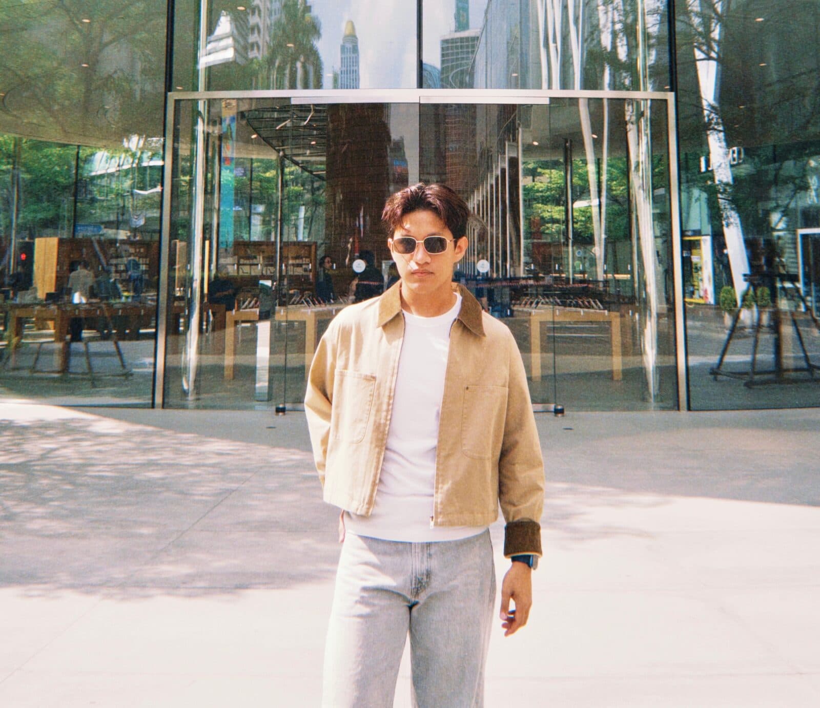 Amer standing in front of a glass storefront in the city